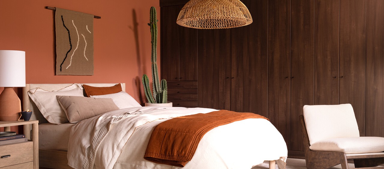 A decorated bedroom with dark orange walls and West Elm furniture.