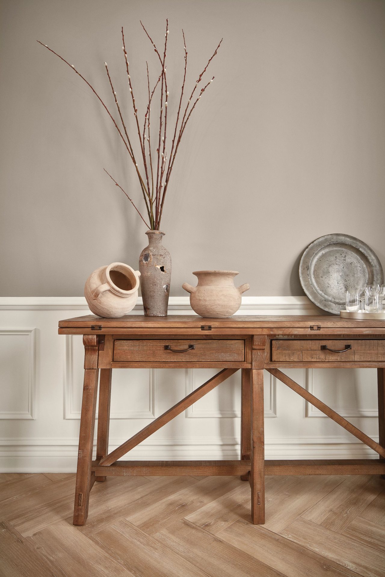 A console table with decor on top along a wall painted Fawn Brindle SW 7640.