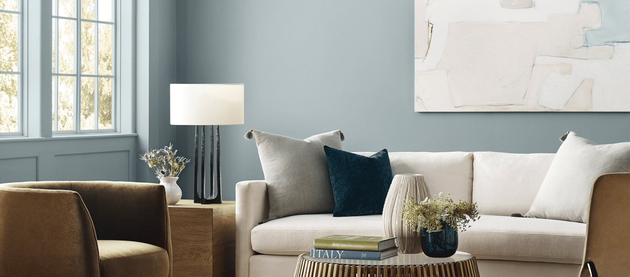 Living room painted in light blue SW paint with a cream colored couch and light brown chair with matching accents.