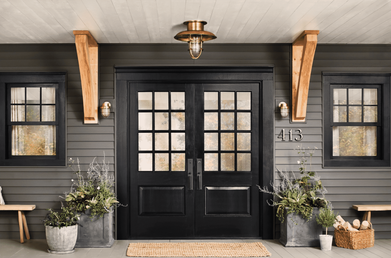 Black double front doors with a large porch with brass accents and potted plants.