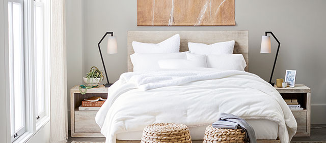 Pottery Barn bedroom with large windows, white bedspread, matching nightstands and lamps, and a large piece of minimal art above the bed, walls painted in Repose Gray SW 7015.
