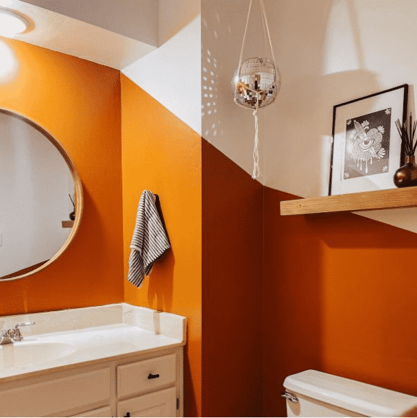 A bathroom with an orange accent wall from @madisonryanrichie.