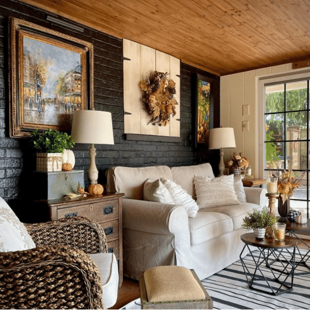 A sunroom with a black brick accent wall with fall decor from @vaughnhillhome.